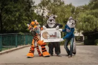 Drei kostümierte Personen ("Fursuiter") stehen im Stadtpark.
